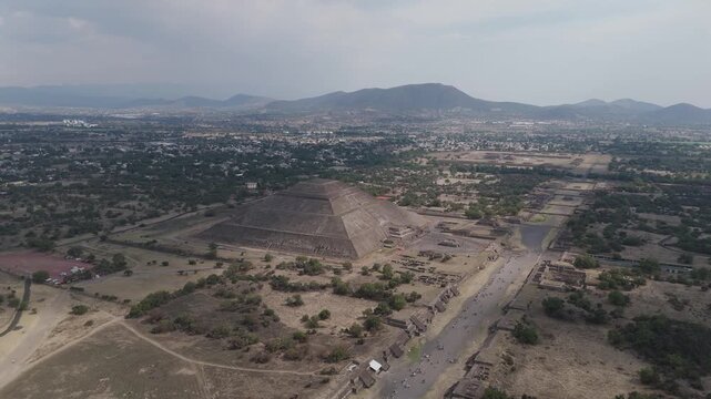 High angle view revealing the ancient aztec city of teotihuacan, featuring the pyramid of the sun and the avenue of the dead, with the modern city visible in the background