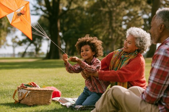 Grandmother helping grandchild fly a kite during family picnic in park