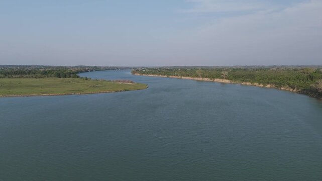 Breathtaking aerial footage flying forward over the wide Tuxpan River in Mexico, revealing the vast green plains and lush tropical forest lining the scenic riverbanks under a clear blue sky