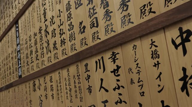 Wooden votive plaques with black Japanese calligraphy of donor names at temple Japan