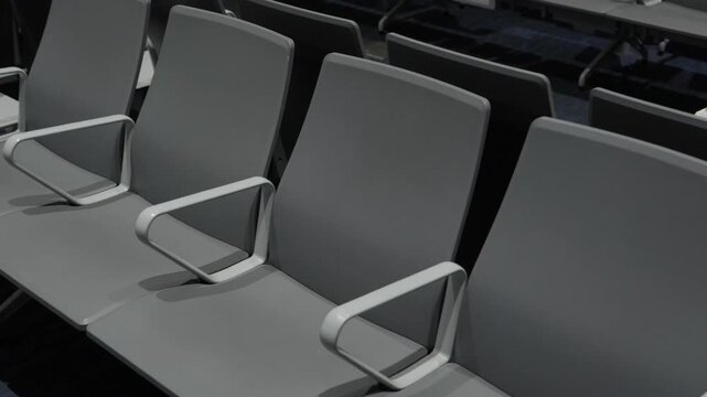 Row of empty gray seats with armrests in airport terminal waiting area