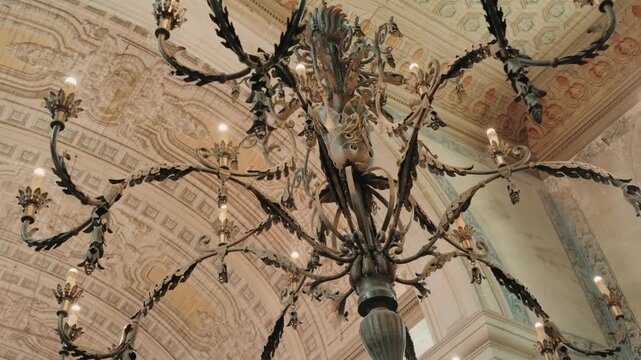 Large antique iron chandelier hanging under a frescoed vaulted ceiling in a palace Portugal
