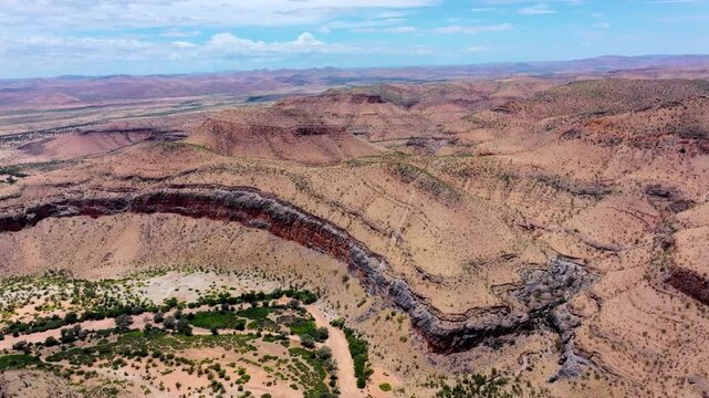 Aerial drone view of incised river meanders in the Kuiseb Canyon, Namib-Naukluft, central Namibia, a green vegetated course looping through deep rock.