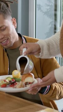 Vertical video: Receiving sauce man in jacket, partner tilting pitcher to eat at home, copy space