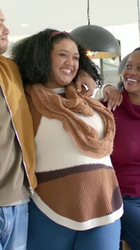 Vertical video: Laughing center lady in scarf leaning to group man placing arm sharing joke at home