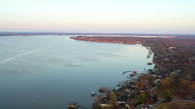Scenic Branson, Missouri lake drone view with shoreline houses, private docks, quiet inlets, and smooth reflective water bordered by tree-covered banks and lake homes.