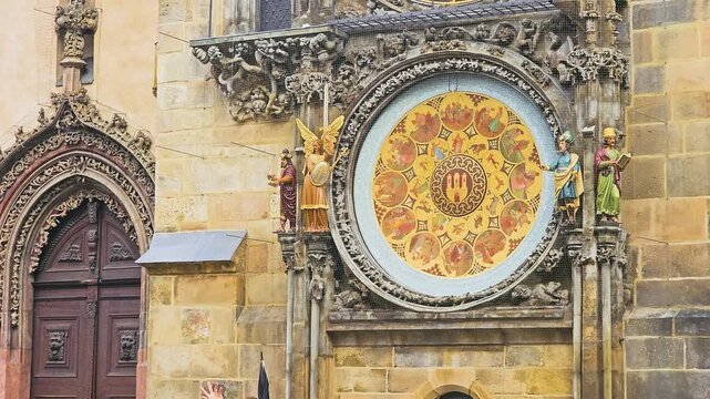 Close-up of the Prague Astronomical Clock calendar dial in Old Town Square, with painted zodiac symbols, carved statues, Gothic stonework, arched doorway, and historic Czech architecture.
