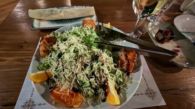 Caesar salad topped with grilled salmon seafood garnished with lemon wedges grated cheese