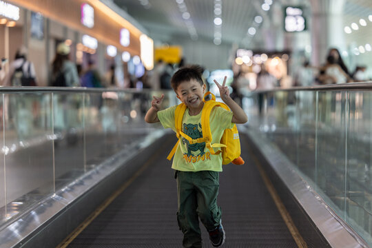Little boy running on moving walkway in airport terminal