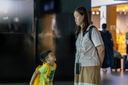 Little boy looking up at mother while waiting in airport terminal
