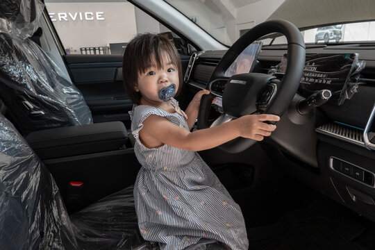Toddler playing in new car interior with pacifier
