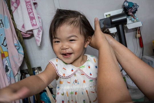 Asian toddler girl smiling having hair styled