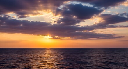 Obraz premium Dramatic ocean sunset with golden light rays and stormy cloudscape