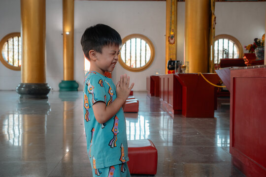 Boy praying with innocent faith in temple