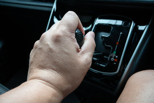 Close-up of a driver's hand shifting gears on an automatic car's gear lever.