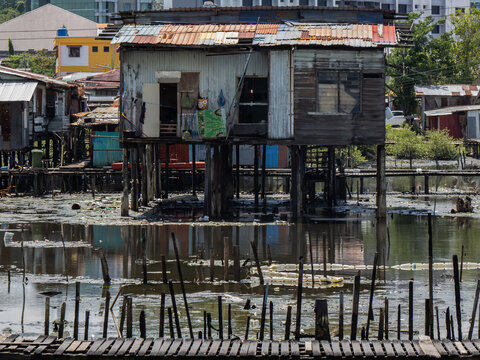 Stilt houses in Sembulan water village, Kota Kinabalu, Sabah, with the city skyline in the background.