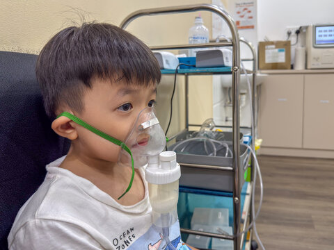 Young boy undergoing nebulizer treatment with a breathing mask at a medical clinic.