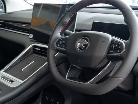 Close-up of a car dashboard, highlighting the steering wheel, infotainment screen, and center console