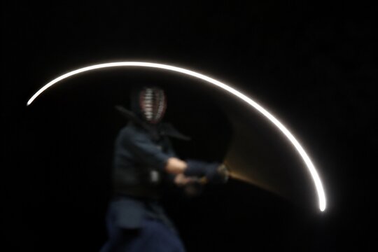 A white arc of light tracing the path of a moving sword.