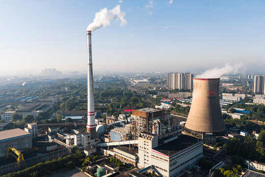 Wuhan Thermal Power Plant featuring gaint nuclear-style cooling towers and smokestacks, emitting heavy steam.  It uses ultra-low emission, cogeneration for green energy transition. China.