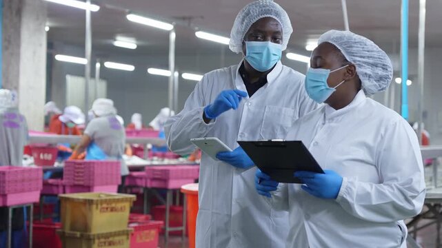 Quality control managers inspecting seafood processing facility, Factory supervisors overseeing food production line, Team of industrial employees wearing sanitary uniform and masks in food factory