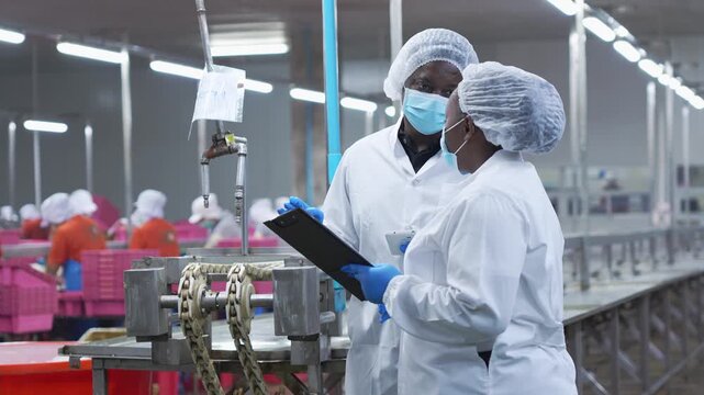 Factory supervisors overseeing food production line, Quality control managers inspecting seafood processing facility, Team of industrial employees wearing sanitary uniform and masks in food factory