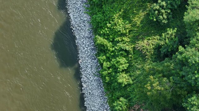 Riprap embankment bordering the Po River near Castelvetro Piacentino, Piacenza, Emilia-Romagna, Italy, revealing exceptionally low water levels during the June 2026 heatwave and drought drone top down