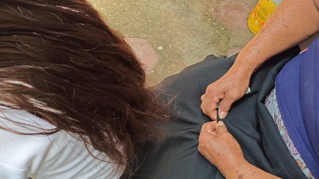 Woman thoroughly checking and cleaning a young girl's hair to remove lice nits