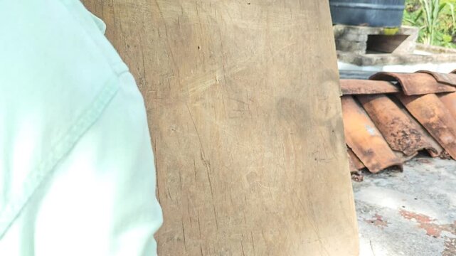 Hand using a wire brush to clean and texture a piece of wood lumber