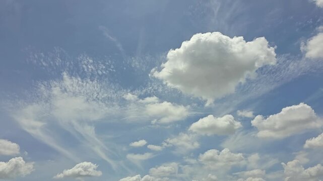 The bright azure sky contrasted with soft white cumulus clouds and strangely shaped cirrus clouds moved slowly. Large, white clouds in the center had a fluffy. Smaller clouds broke apart into wisps.
