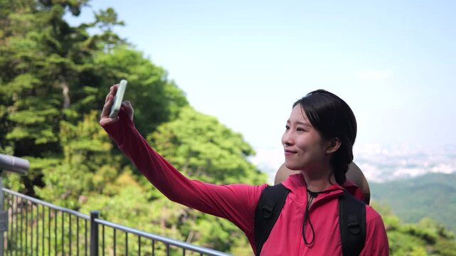 高尾山の中腹で自撮りをする笑顔の女性