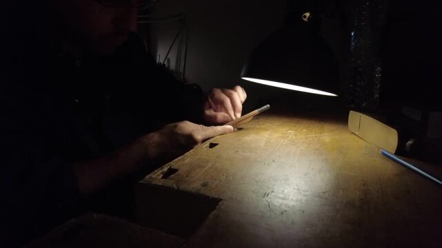 Luthier shapes a violin bow by hand at a workbench in Cremona, Lombardy, Italy, refining pernambuco wood with traditional bow-making techniques and precision craftsmanship, close-up static shot.