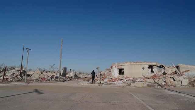 Wide View of Person in Black Standing Amid Desolate Dead Trees in Ghost Town Ruins of Villa Epecuen Argentina