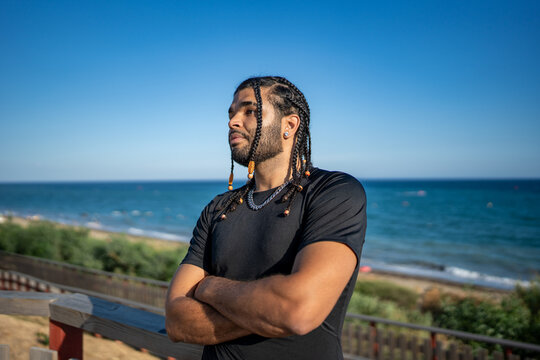 Confident man with braided hair looking at ocean view