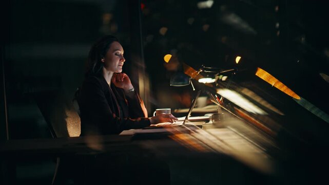 Thoughtful employee sitting night working late. Pensive woman texting laptop