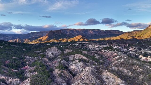 Wide Rocky Valley At Golden Hour With Layered Ridges And Warm Light Pockets, Scrubby Vegetation And Rocky