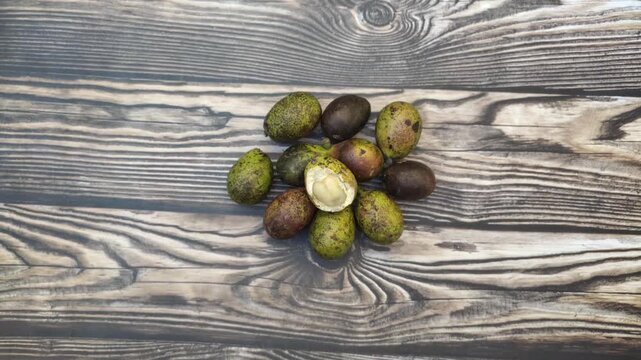 A bunch of fresh Matoa or Pometia pinnata fruit with a wooden table in the background