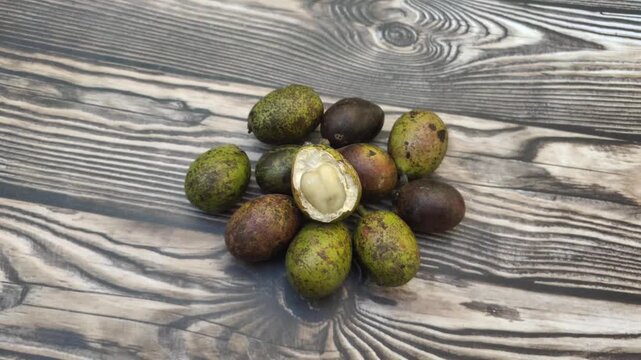A bunch of fresh Matoa or Pometia pinnata fruit with a wooden table in the background