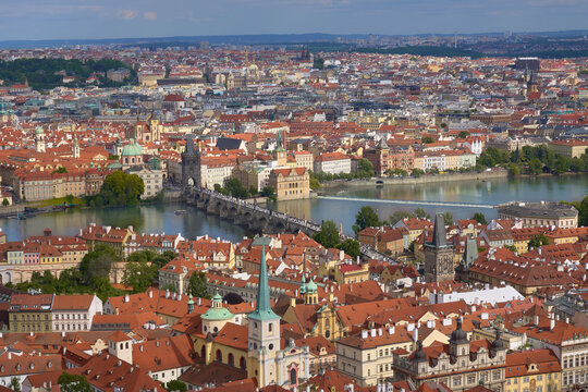 Aerial scenic view of Prague Old Town, showing the Charles Bridge crossing the Vltava River and the densely packed historic buildings.