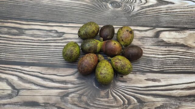 A bunch of fresh Matoa or Pometia pinnata fruit with a wooden table in the background