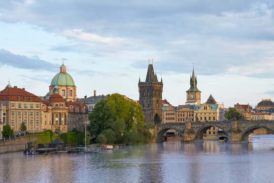 Close-up view of the Old Town Bridge Tower and Charles Bridge crossing the Vltava River in Prague, Czech Republic, during evening twilight.