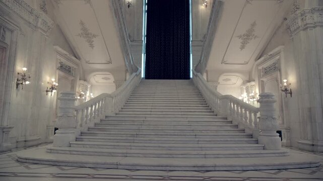 Grand marble staircase in palace of parliament bucharest with white columns and ornate architecture.