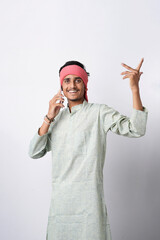 Fototapeta premium happy young indian farmer using smartphone standing on white background