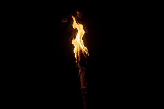 A single burning torch creating a focal point of light in darkness.