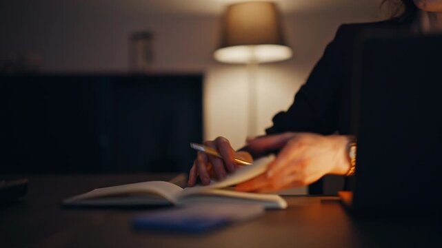 Overtime lawyer making notes looking monitor laptop at dark workplace closeup
