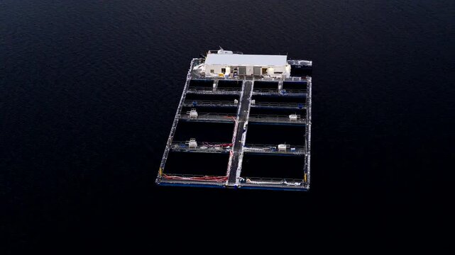 Top orbiting aerial shot around aquaculture cod farm in Norway with marine pens