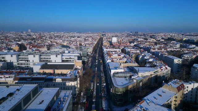 berlin city showing snow covered rooftops, buildings, and a long shopping street schloss str in winter. Wonderful aerial view fly reverse panorama drone