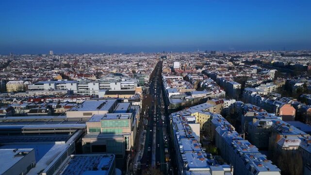berlin city showing snow covered rooftops, buildings, and a long shopping street schloss str in winter. Fabulous aerial view overflight flyover panorama drone