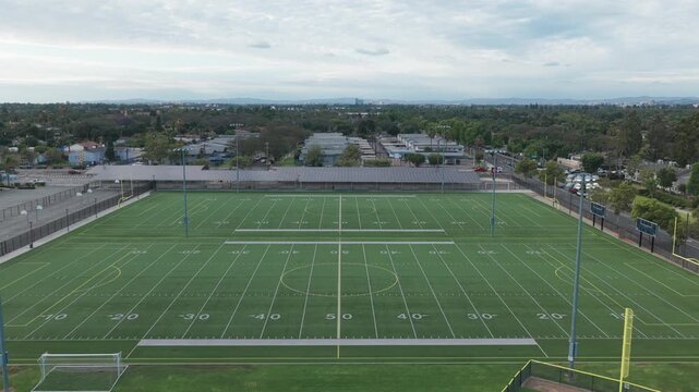 Wide aerial push-in shot of football fields at a high school in Southern California. 4K
