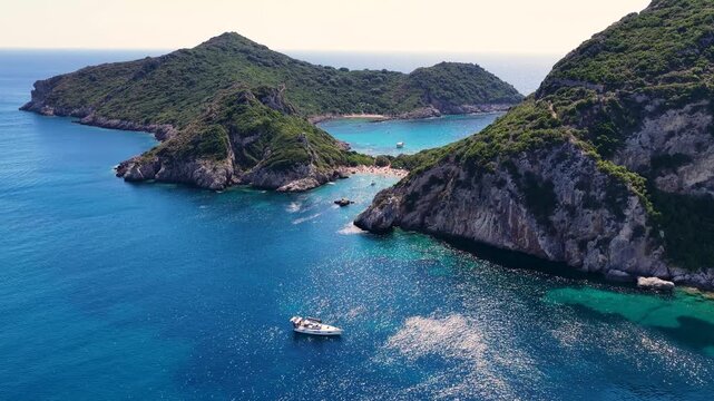 Aerial view of Porto Timoni beach cove in Corfu Greece. Turquoise sea bay with green cliffs, hiking path and tourists swimming on summer vacation holiday destination microstock drone shot